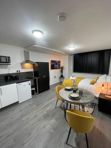 a room with a bed and a table and a kitchen at Luxury new studio flat in Luton