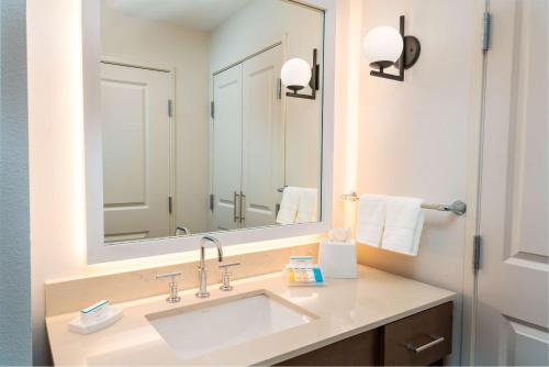 uma casa de banho com um lavatório e um espelho grande em Homewood Suites By Hilton Rancho Cordova, Ca em Rancho Cordova