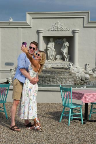 a man and a woman taking a picture in front of a fountain at Villa di Casa - Boutique Hotel in Wellington