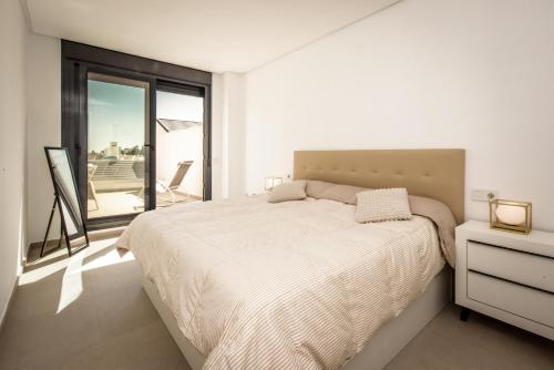 een witte slaapkamer met een bed en een balkon bij Casa Laura Estepona in Estepona