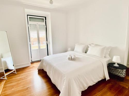 a white bedroom with a large white bed with two wedding rings on it at SATURdAYS in Lisbon