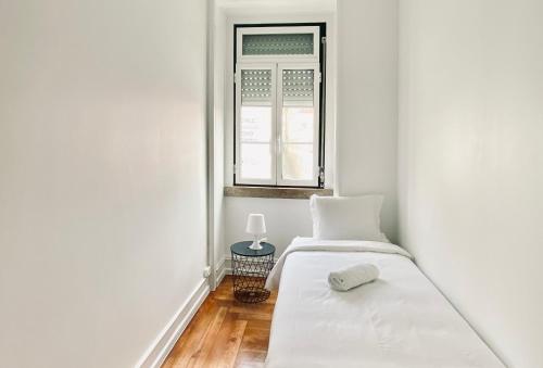a white bedroom with a bed and a window at SATURdAYS in Lisbon