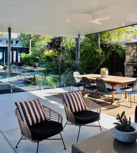 a patio with chairs and a table and a table and a table and chairs at Caba Beach Casa in Cabarita Beach