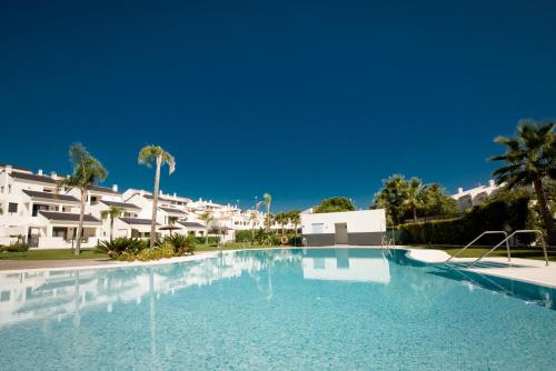 een groot zwembad met gebouwen op de achtergrond bij Casa Laura Estepona in Estepona