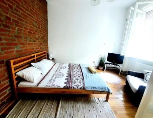 a bedroom with a bed and a brick wall at One bedroom by the Park Old Town Belle Vue Timisoara in Timişoara