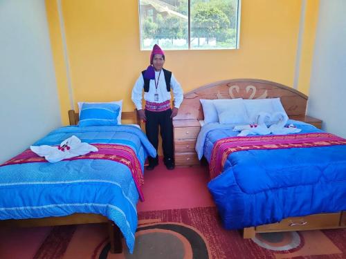 a woman standing between two beds in a room at Taquile Inti Raymi Lodge in Huillanopampa