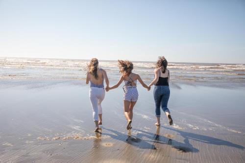 three women walking on the beach holding hands at Quinault Beach Resort & Casino in Ocean Shores