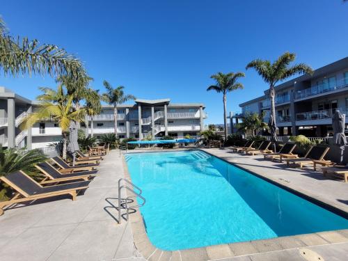 a swimming pool with lounge chairs and a resort at Marina Park Apartments Whitianga in Whitianga