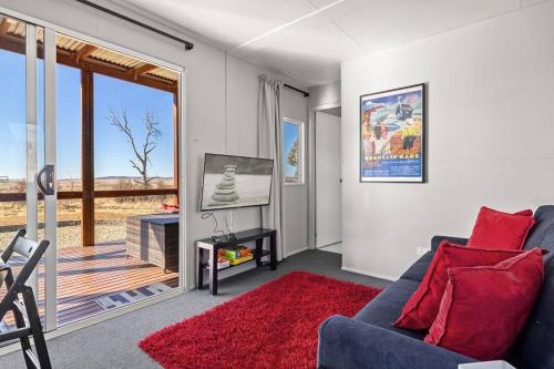 a living room with a blue couch and a television at Bliss Cabin @ Belaxed Farm Berridale in Berridale