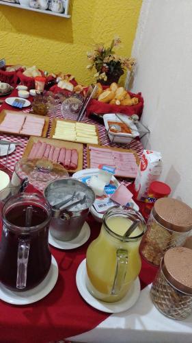 een tafel met etenswaren op een rode tafelkleed bij Pousada Linda Borboleta in Conservatória