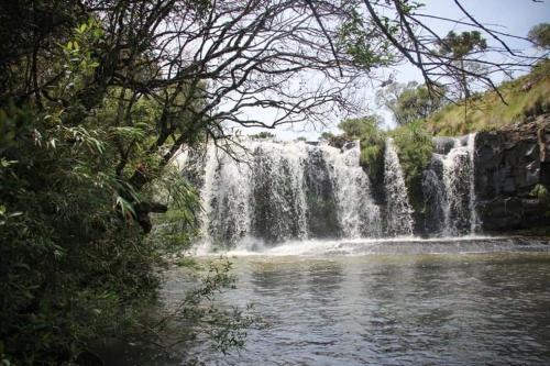 a waterfall in the middle of a body of water at Pousada Recanto da Cascata - Cabana Platano in São Joaquim