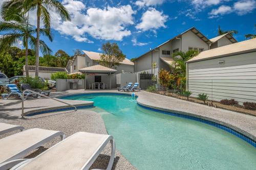 a swimming pool with chairs and a house at Noosa Entrance Waterfront Resort in Noosaville