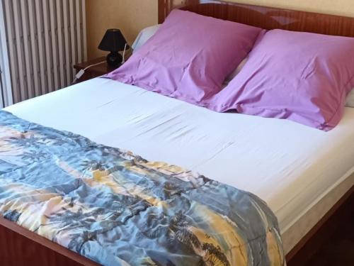 1 cama con almohadas moradas y sábana blanca en Gîte Saint-Vincent-du-Lorouër, 4 pièces, 6 personnes - FR-1-410-200, en Saint-Vincent-du-Lorouër