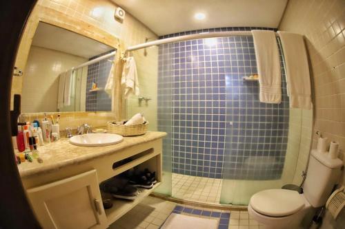 y baño con ducha de azulejos azules y aseo. en Casa 70 Mar Paraíso, en Porto Seguro