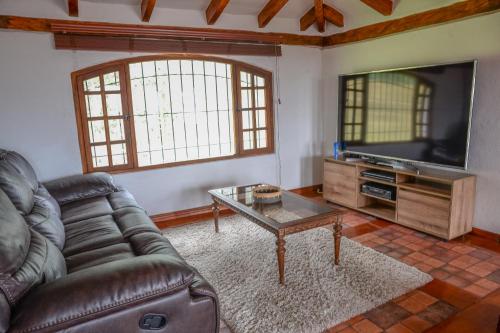 ein Wohnzimmer mit einem Sofa und einem Flachbild-TV in der Unterkunft Hacienda Turística La Morería in Amaguaña