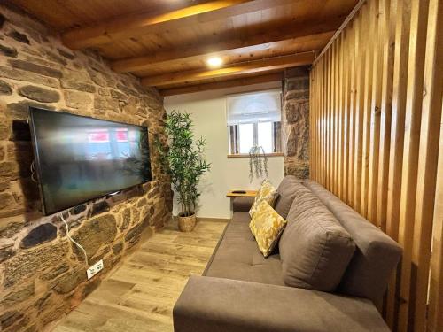 uma sala de estar com um sofá e uma televisão de ecrã plano em Casa d'avó Coragem em Seia
