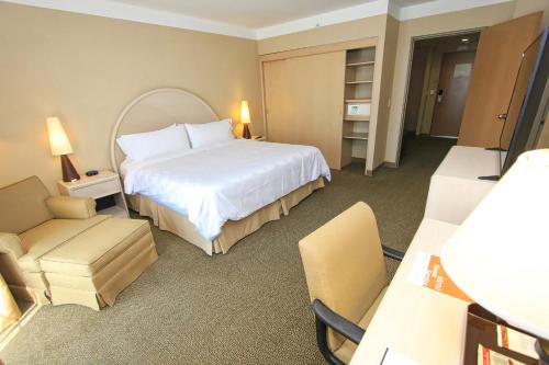 a hotel room with a large bed and a chair at Holiday Inn Leon-Convention Center by IHG in León