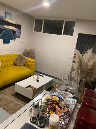 - un salon avec un canapé jaune et une table dans l'établissement Apartment in Vibrant Maboneng, à Johannesbourg