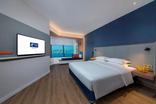 a bedroom with a large white bed and a flat screen tv at Holiday Inn Express Xiamen Airport Zone by IHG in Xiamen