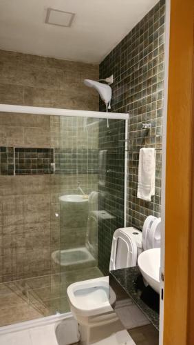 a bathroom with a shower and a toilet and a sink at Pousada Portomares in Porto De Galinhas