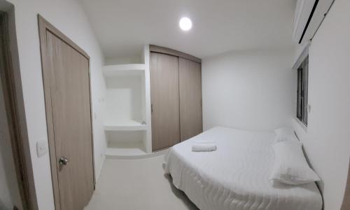a white bedroom with a bed and a bathroom at Hermoso apartamento cerca a las playas de Marbella en Cartagena in Cartagena de Indias