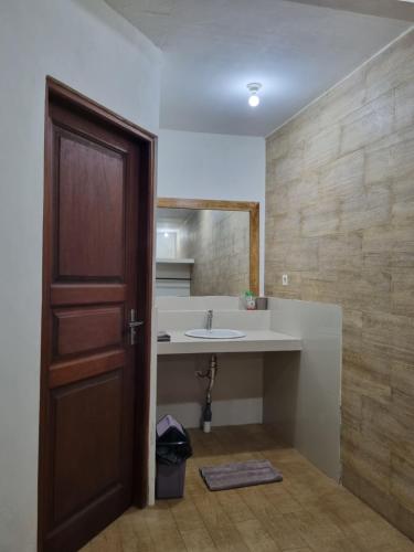 un bagno con lavandino, specchio e porta di Mambul Garden Private Villa a Sangeh