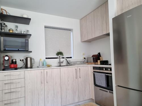 a kitchen with wooden cabinets and a stainless steel refrigerator at CBD 2BDR 2Bath Casino TownHall TePae Convention center FREE carpark in Christchurch