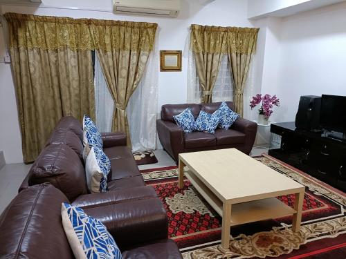 a living room with a leather couch and a coffee table at Homestay Kesang Sungai Rambai in Kampong Sungai Rambai
