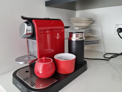 a red mixer on a counter with cups and plates at CBD 2BDR 2Bath Casino TownHall TePae Convention center FREE carpark in Christchurch