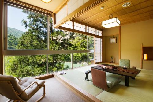 a living room with a table and a large window at Kurobe UnazukiOnsen Togen in Kurobe