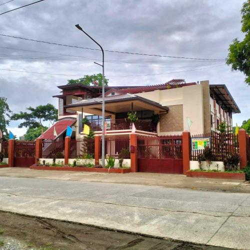 a house with a red fence in front of it at Tessie's Home Stay Bed & Breakfast in Puerto Princesa City