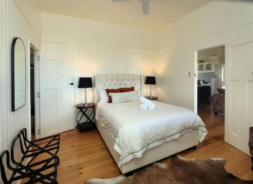 a bedroom with a large white bed and two lamps at Pandanus House in Bargara