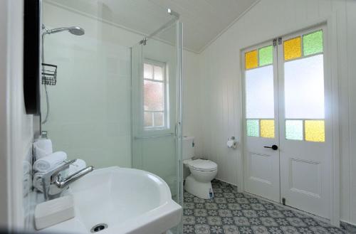 a white bathroom with a tub and a toilet at Pandanus House in Bargara