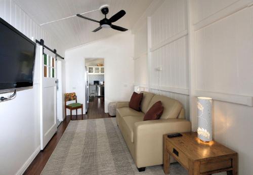 a living room with a couch and a ceiling fan at Pandanus House in Bargara