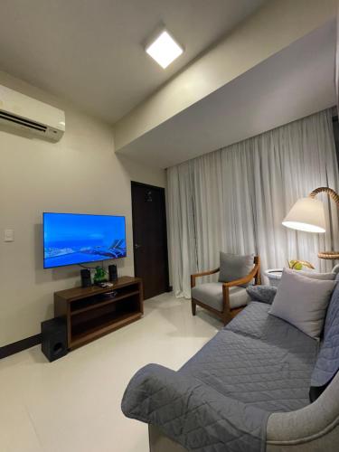 sala de estar con sofá y TV de pantalla plana en The Beach Suite at The Mactan Newtown en Lapu Lapu City