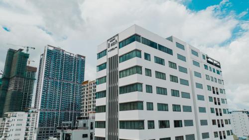 a tall white building in front of some buildings at The ONRA Hotel in Phnom Penh