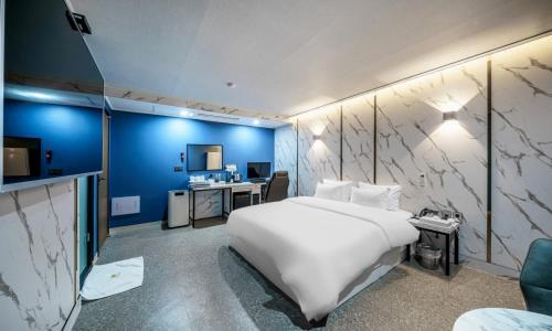 Schlafzimmer mit einem großen weißen Bett und einem Schreibtisch in der Unterkunft G7 Hotel in Tongduch'ŏn