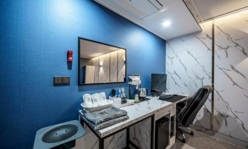 an office with a blue wall with a desk and a mirror at G7 Hotel in Dongducheon