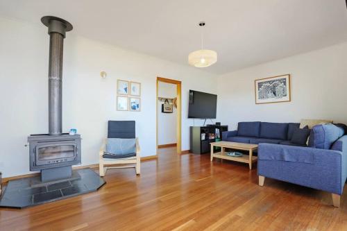 a living room with a blue couch and a fireplace at Pambula Family Beach House in Pambula Beach