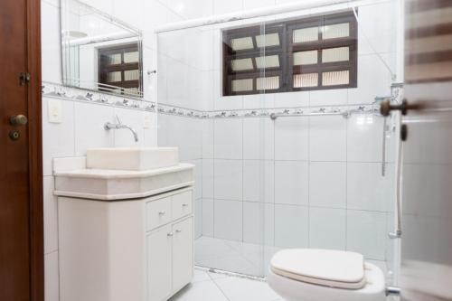a white bathroom with a toilet and a sink at casa completa enseada guaruja in Guarujá