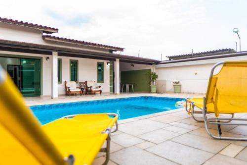 a villa with a swimming pool and yellow chairs at casa completa enseada guaruja in Guarujá