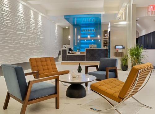 a lobby of a hotel with chairs and a table at voco Fiorello - LaGuardia East by IHG in Queens