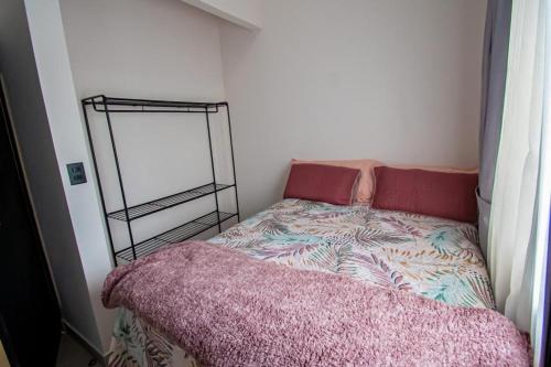 a small bedroom with a bed and a mirror at Apartamentos Bukare in Quepos