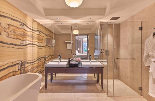 a bathroom with two sinks and a tub and a shower at Pullman Singapore Orchard in Singapore