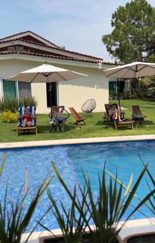 una piscina con sillas y sombrillas junto a una casa en Quinta Los Caballos, en Ajijic