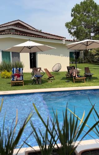 a pool with chairs and umbrellas next to a house at Quinta Los Caballos in Ajijic