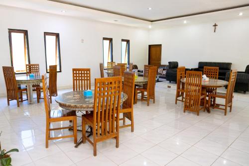 una sala da pranzo con tavoli e sedie in legno di Hotel Green Prundi a Labuan Bajo