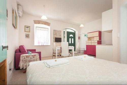 a bedroom with a white bed and a kitchen at Studio Stella in Rovinj