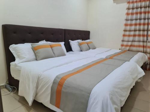 duże łóżko z pomarańczową i białą pościelą i poduszkami w obiekcie Sekinchan SeaView Homestay L117 High View w mieście Sekinchan