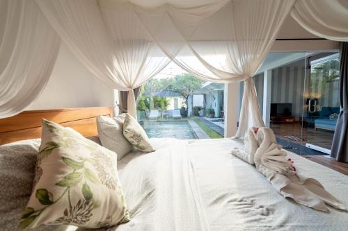 Un dormitorio con una cama con sábanas y almohadas blancas. en La Fortuna, en Seminyak